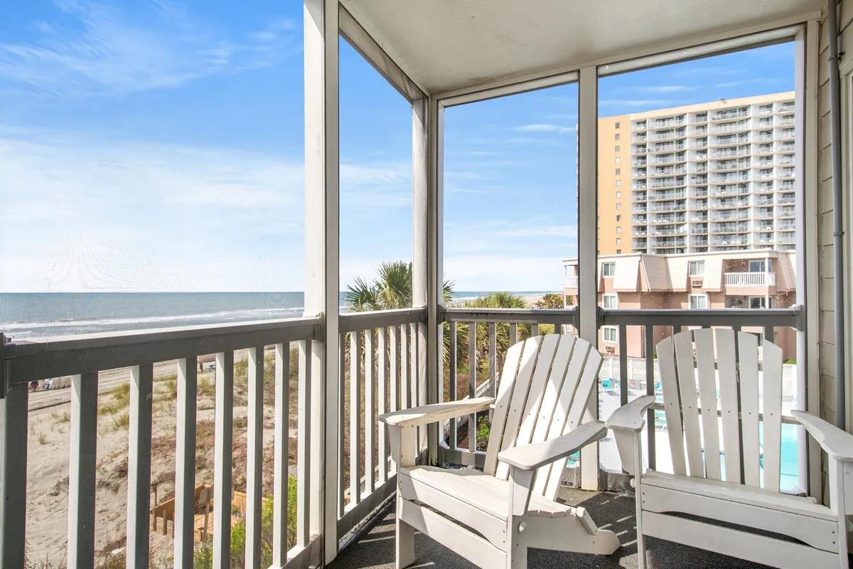 The hero image captures a tranquil oceanfront setting with inviting Adirondack chairs overlooking sparkling waters, a palm-framed pool area, and sweeping views of the shoreline. The scene evokes relaxation, offering glimpses of sunrise colors over the horizon and the promise of peaceful mornings or memorable evenings spent on the balcony.