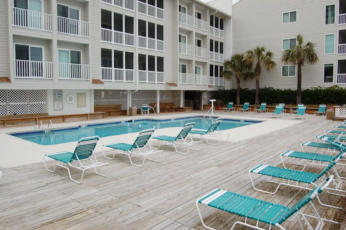 A sparkling resort swimming pool surrounded by lounge chairs and balconies, inviting guests to swim, sunbathe, and unwind after a day of exploration. The setting suggests relaxation and family-friendly amenities.